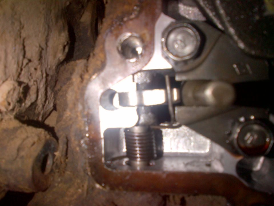 Close-up of a rusty metal bracket with a spring-loaded mechanism and a bolt