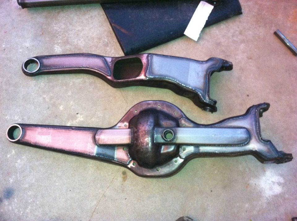 Two metal automotive differential housings and axle components laid on a concrete floor