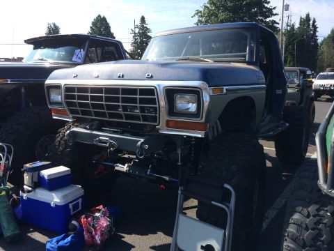 1989 Ford Bronco - Front view of a heavily modified Ford pickup truck with oversized tires and a winch.