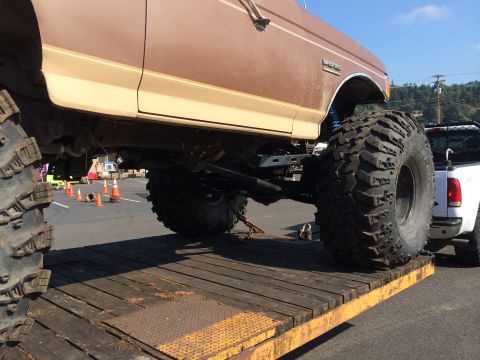 1989 Ford Bronco - 1989 Ford Bronco loaded onto a trailer, showing its lifted suspension and massive tires.