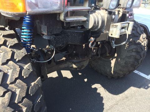 1989 Ford Bronco - Close-up view of the front suspension and winch system on a heavily modified off-road vehicle.