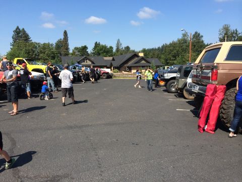1989 Ford Bronco - Several off-road vehicles are gathered in a parking lot on a sunny day.