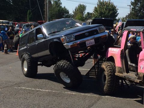1989 Ford Bronco - Modified Toyota 4Runner on display at an off-road show, interacting with a custom pink truck.