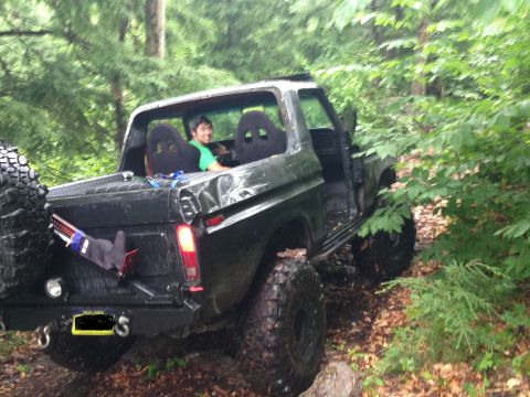 1979 Ford Bronco - Modified 1978 Ford Bronco with racing seats and large tires off-road in woods.