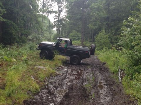 1979 Ford Bronco - This lifted Ford Bronco is navigating a challenging muddy trail through a forest.
