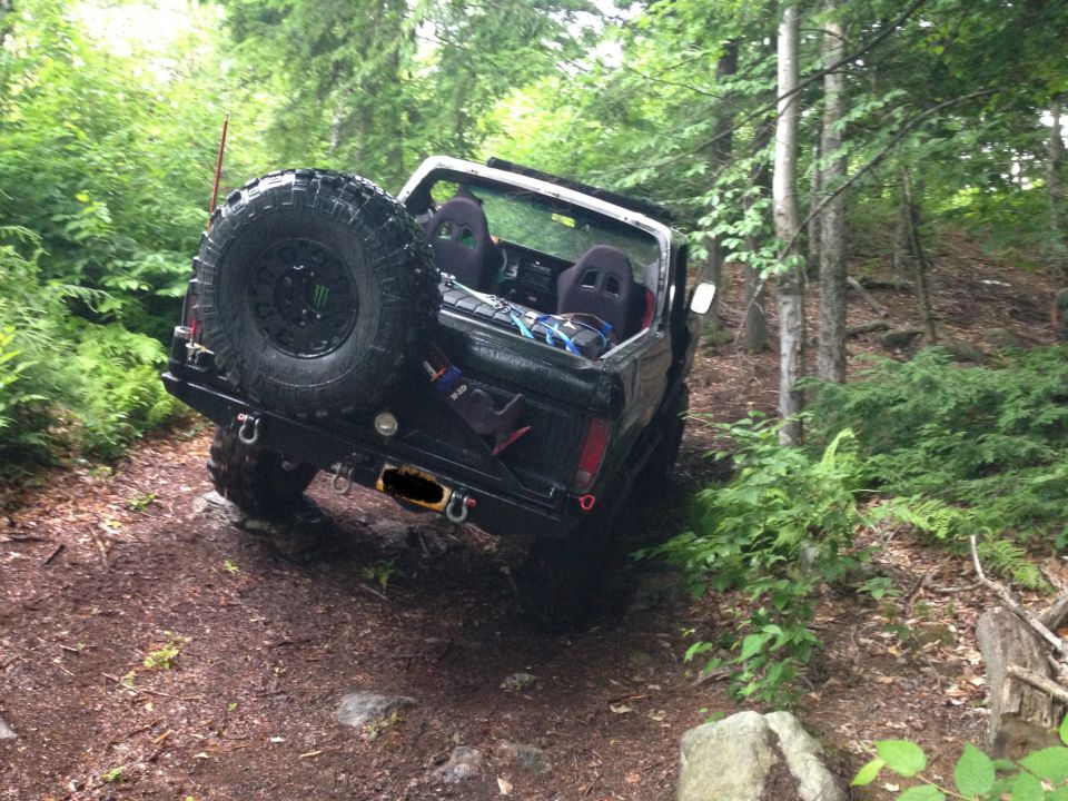 Black SUV with spare tire on rear, off-roading in woods