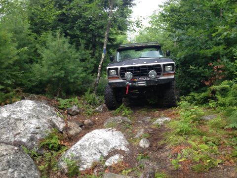 1979 Ford Bronco - This 1979 Ford Bronco is shown off-roading on a wooded trail with large rocks.