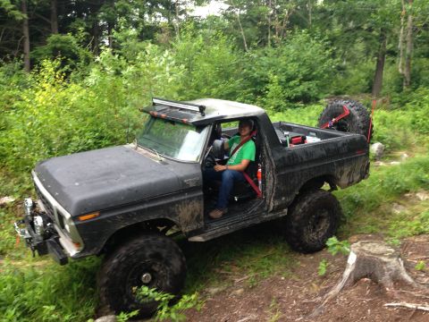 1979 Ford Bronco - Driver in a green shirt navigates a muddy trail in a modified Ford Bronco.