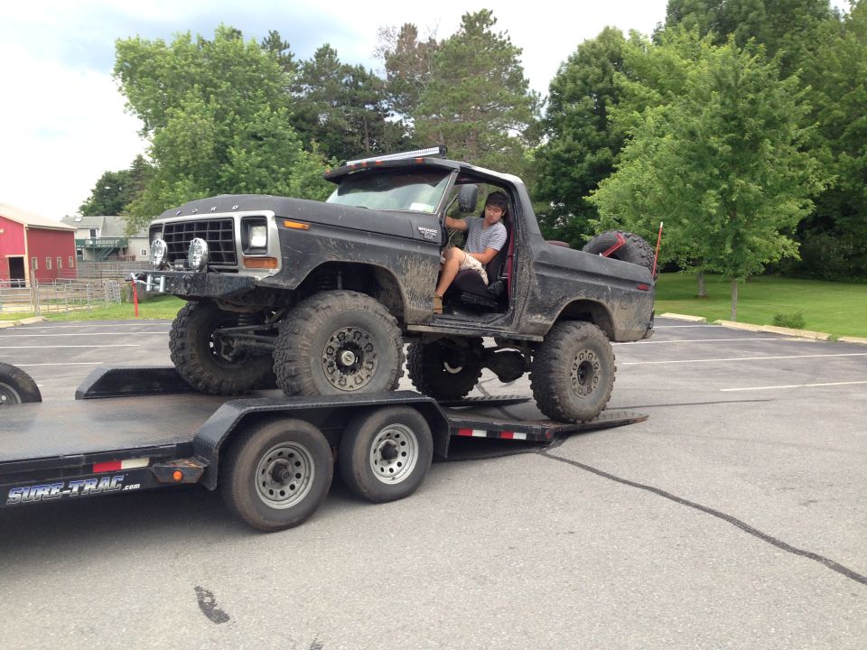 Black 1979 Ford Bronco on trailer, 3q-front view. Lifted with large tires