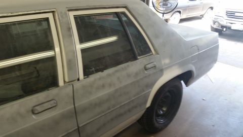1991 Ford LTD Crown Victoria - Side view of a gray sedan in primer, with another vehicle visible in the background.