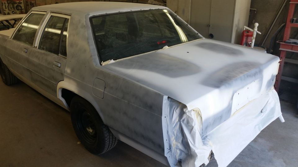 Car body covered in primer, with rear bumper taped off. It's in a workshop