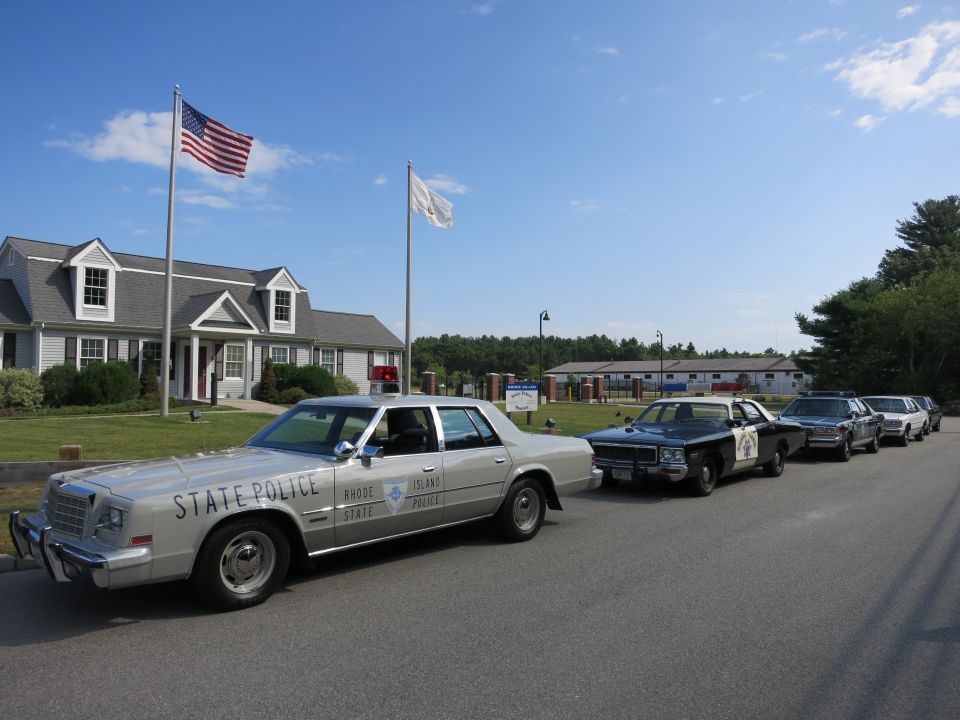 Silver State Police sedan leading row of cruisers by flagpole