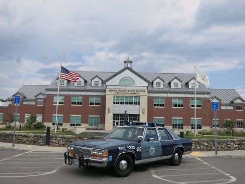1991 Ford LTD Crown Victoria - blue State Police sedan marked 90E sits in a parking lot in front of the Rhode Island State Police Public Safety Complex.