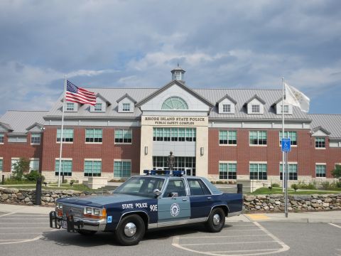 1991 Ford LTD Crown Victoria - Front three-quarter view of a blue and light-blue State Police sedan parked before the Rhode Island State Police Public Safety Complex.