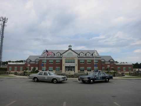 1991 Ford LTD Crown Victoria - silver state police sedan and a blue state police sedan parked side by side in front of the Rhode Island State Police Public Safety Complex.