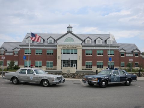 1991 Ford LTD Crown Victoria - silver State Police sedan and a blue State Police sedan parked side by side in front of the Rhode Island State Police Public Safety Complex.