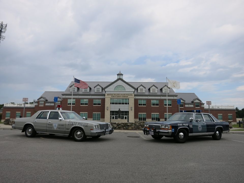 Silver and blue State Police sedans facing forward at Rhode Island complex