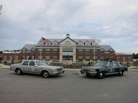 1991 Ford LTD Crown Victoria - silver State Police sedan and a blue State Police sedan parked side by side in the lot before the Rhode Island State Police complex.