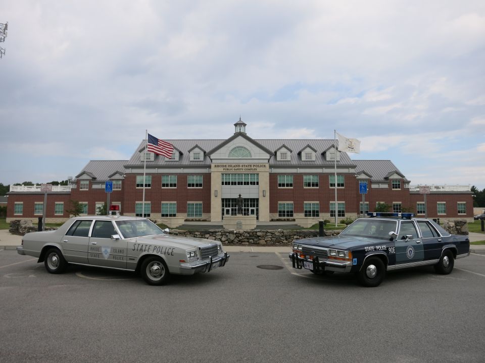 Silver and blue State Police sedans angled at Rhode Island State Police complex