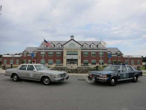 1991 Ford LTD Crown Victoria - silver State Police sedan and a blue State Police sedan parked close together in front of the Rhode Island State Police complex.