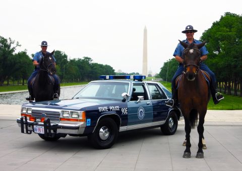 1991 Ford LTD Crown Victoria - blue State Police 90E sedan flanked by two mounted officers on horseback with the Washington Monument in the background.