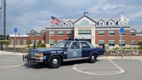 1991 Ford LTD Crown Victoria - Blue-over-silver Ford LTD Crown Victoria police sedan marked 'STATE POLICE 90E' with a Massachusetts State Police door seal, parked at a 3/…