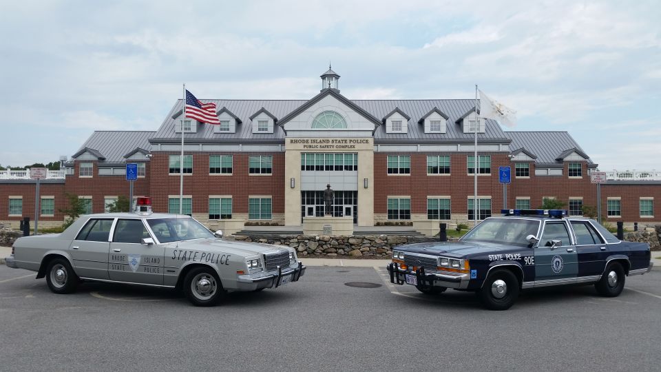 Silver Dodge and blue Ford state police cruisers outside Rhode Island State Police HQ