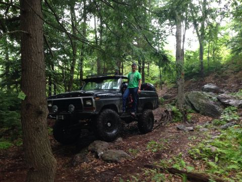 1979 Ford Bronco - A black 1979 Ford Bronco is shown off-road with a person standing on its running board.