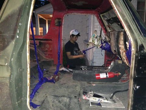 1979 Ford Bronco - A person works on the interior of a vehicle that appears to be undergoing restoration or repair, with parts removed and wiring exposed.