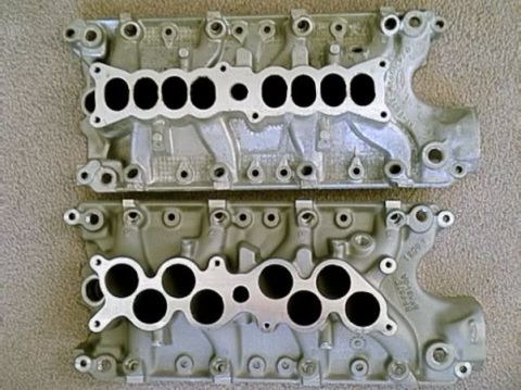 1993 Ford Taurus - Two engine intake manifolds are shown, likely for a Ford vehicle, resting on a carpeted floor.