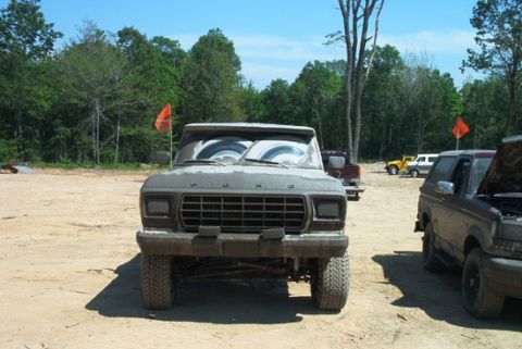 1979 Ford Bronco - A muddy Ford F-Series truck is parked outdoors with other vehicles in the background.