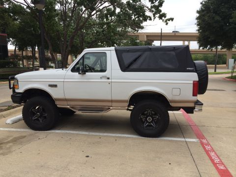 1996 Ford Bronco - This white Ford Bronco features a black soft top and a spare tire mounted on the rear tailgate.