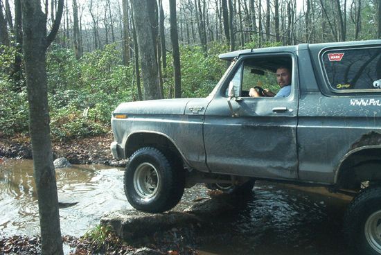 1979 Ford Bronco driving off-road through water and rocks