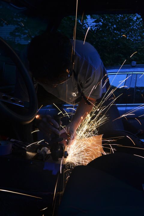 1979 Ford Bronco - A person works on the interior of a vehicle with an angle grinder, creating a shower of sparks.