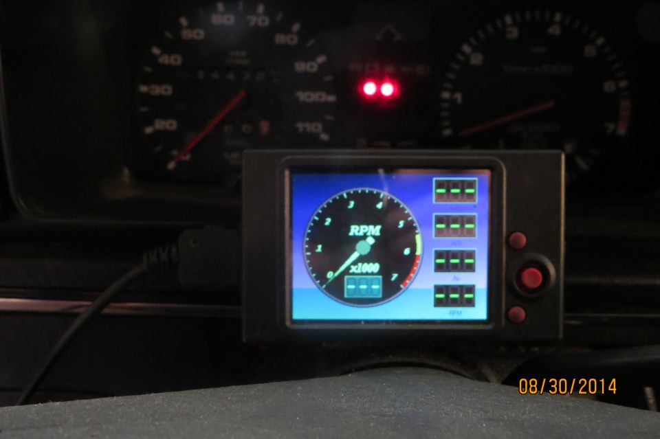 Digital gauge shows RPM and other readings. Speedometer and tachometer are visible in background