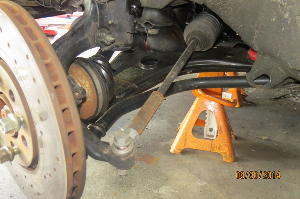 Close-up of a car's front suspension with a brake rotor and tie rod end, supported by an orange jack stand