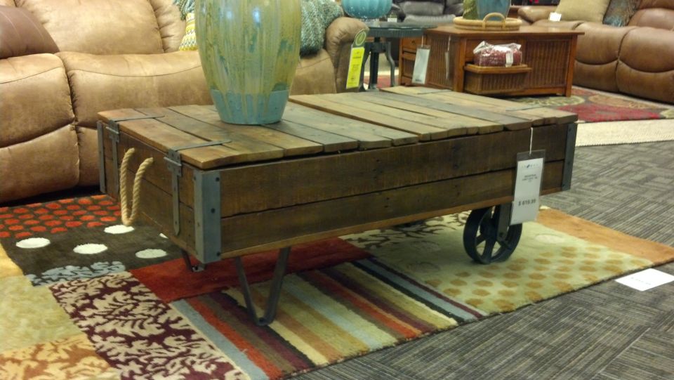 Wooden coffee table with rope handles and metal wheels on a patchwork rug