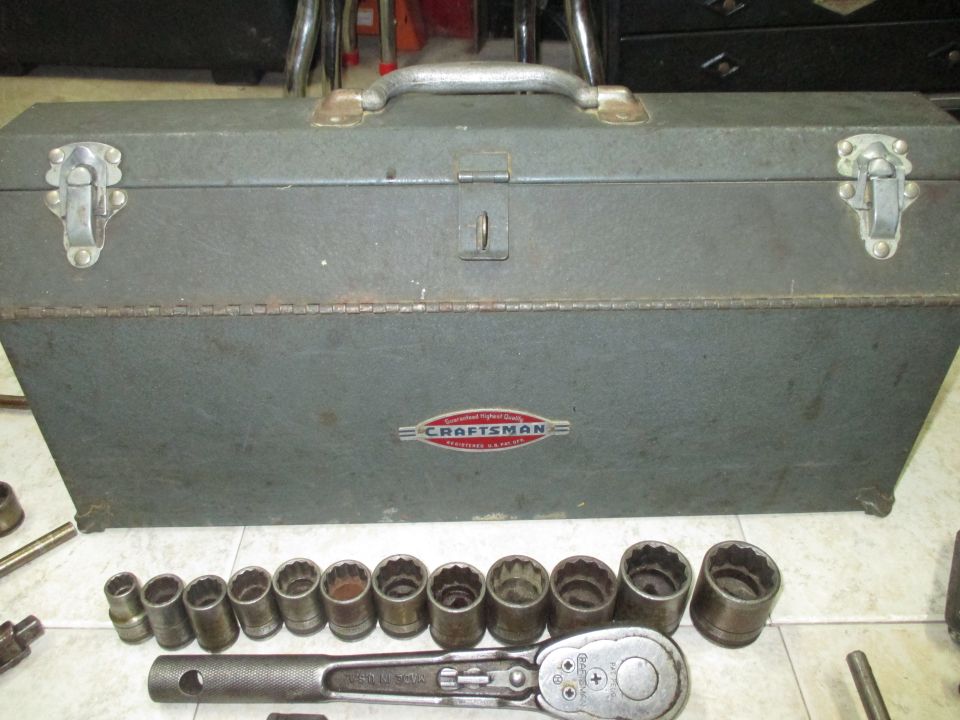 Gray metal toolbox with a row of socket wrenches and a ratchet in front. The toolbox has a red and silver Craftsman logo