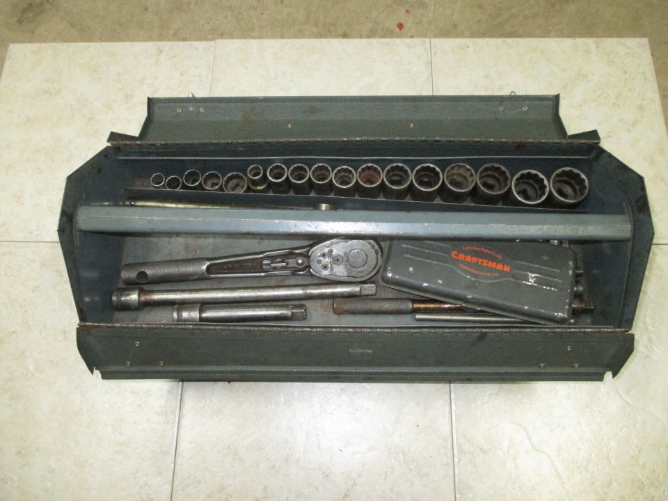 Open metal tool chest filled with sockets and a ratchet. Craftsman logo visible on a small box
