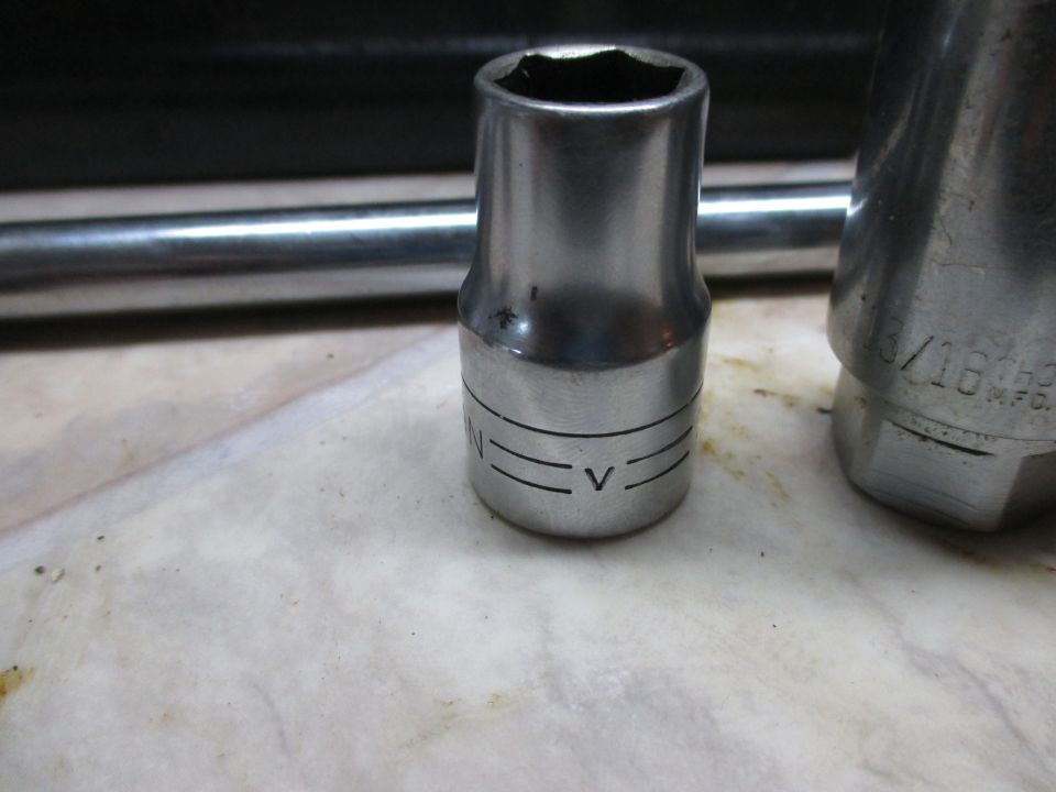 Close-up of two metal sockets and a metal bar on a textured surface