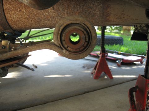 1994 Ford Bronco - Close-up view of a vehicle's rusty leaf spring bushing, with jack stands visible.