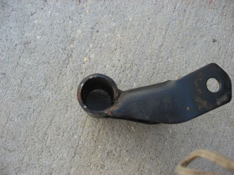 1994 Ford Bronco - A single automotive part, likely a bracket, rests on a textured concrete surface.