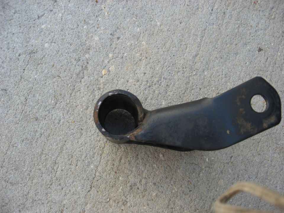 Metal bracket with two holes, one large and one small, lying on concrete