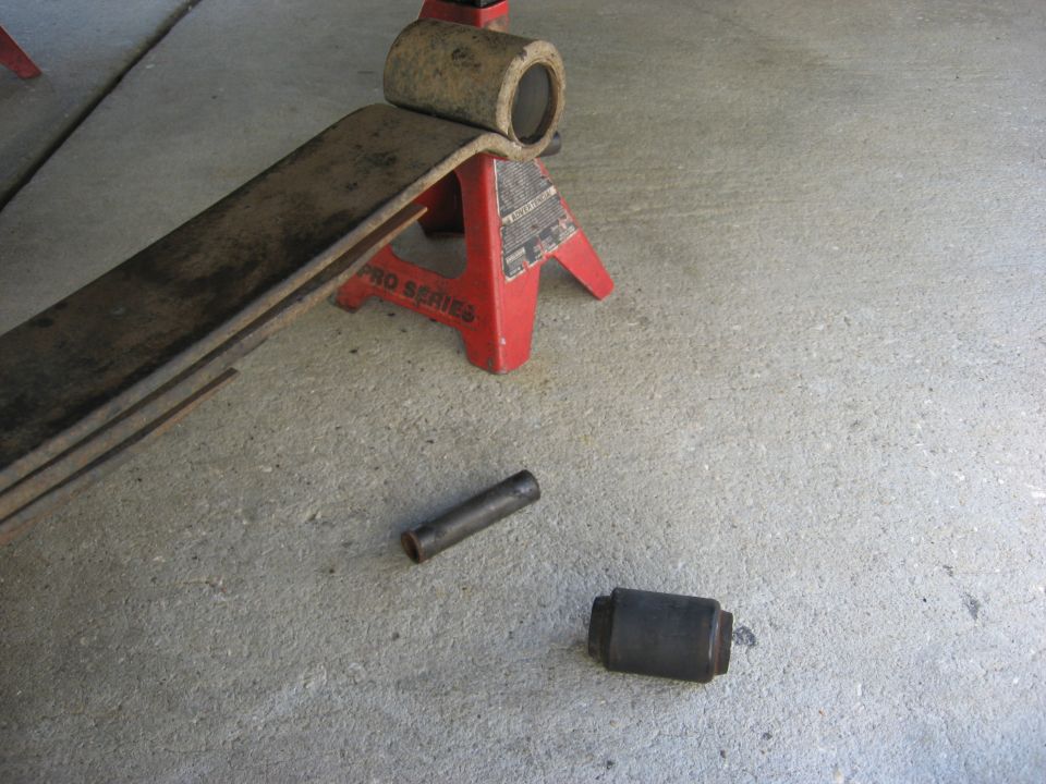 Leaf spring on red jack stand with two bushings on concrete floor