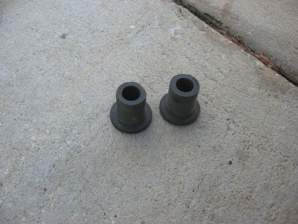 Two black rubber bushings on a concrete surface