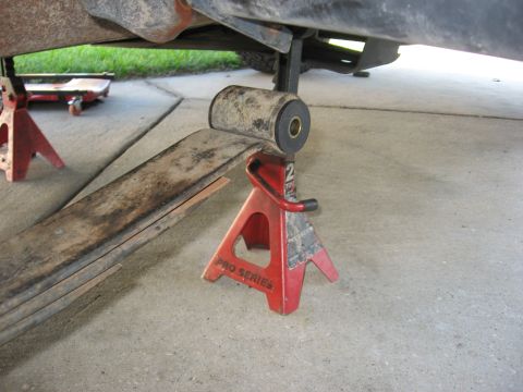 1994 Ford Bronco - A close-up view of a leaf spring bushing supported by a red jack stand, indicating maintenance work on the vehicle's suspension.