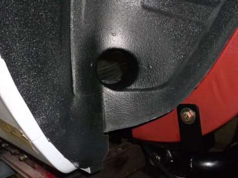 1967 Ford Mustang - Close-up view of an automotive undercarriage part, showing textured black coating and a red painted section.