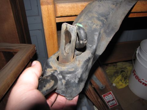 1992 Ford F-150 - A hand holds a worn metal vehicle part, showing rust and wear. Other items are visible in the background.