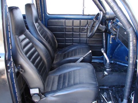 1964 Volkswagen Beetle - The interior of a blue vehicle features black racing seats, a roll cage, and a manual shifter.