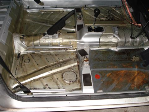 1985 Volkswagen GTI - The bare interior floor pan of a vehicle, showing the transmission tunnel and handbrake assembly.